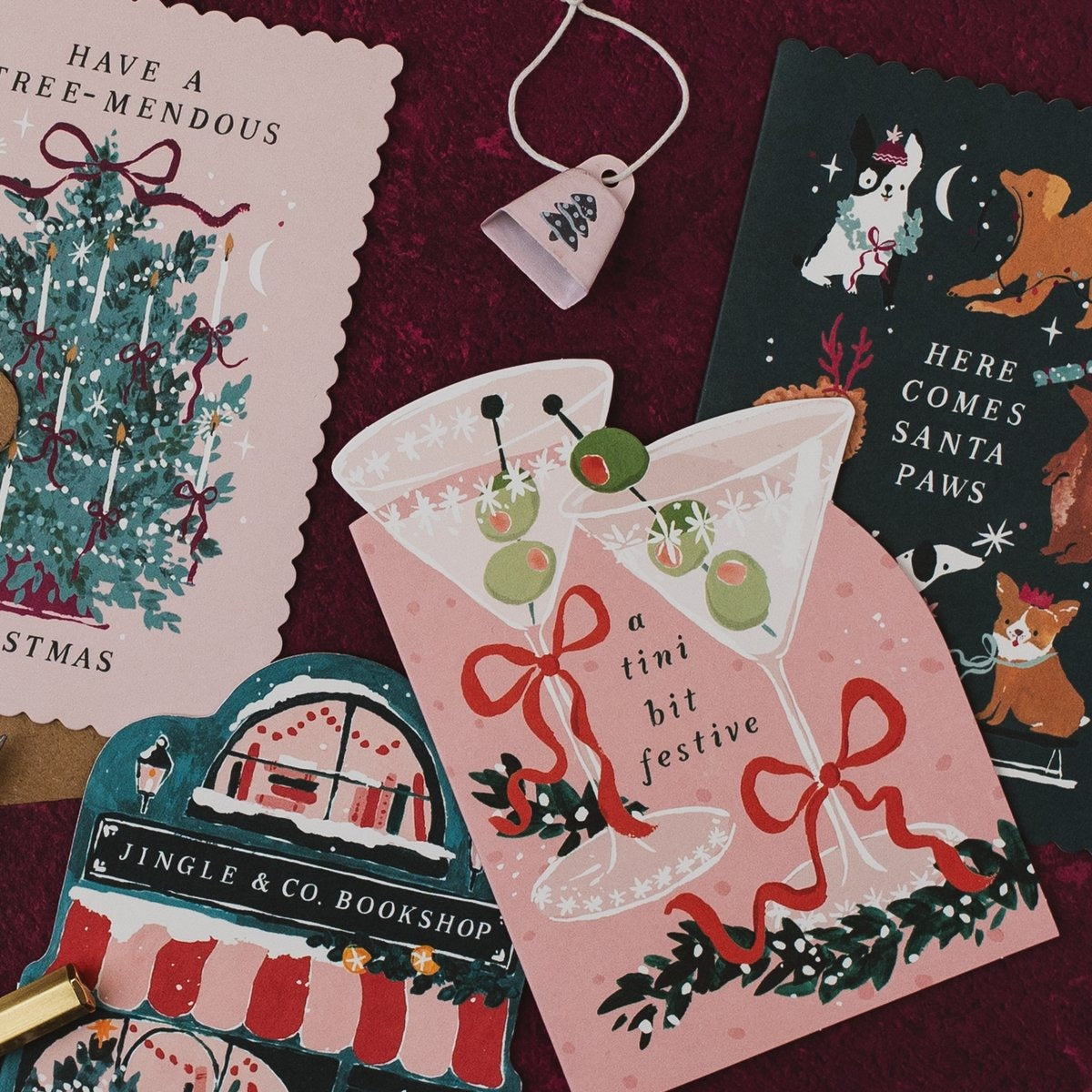 Here Comes Santa Paws dogs Christmas card on a deep red background with Tree-mendous, martini and Jingle & Co bookshop Christmas cards