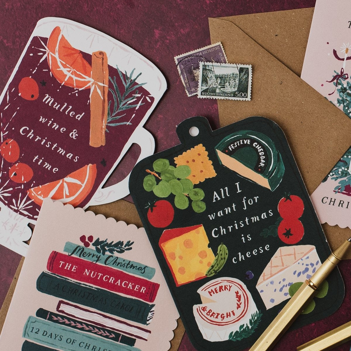 Mulled wine & Christmas time shaped card on a deep red background with cheeseboard and Bookish Christmas cards