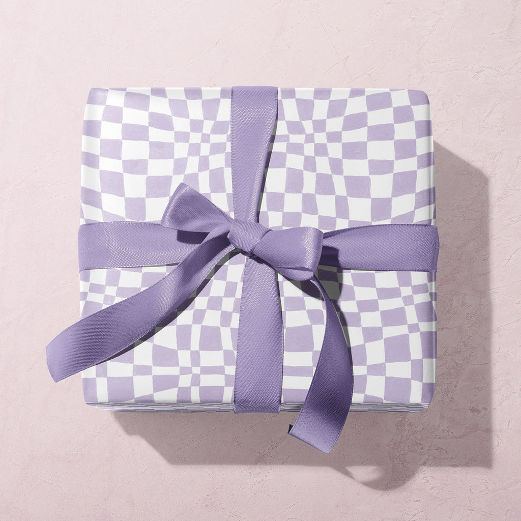 A lilac checkerboard print on wrapping paper from the female birthday wrapping paper collection at Sister Paper Co.