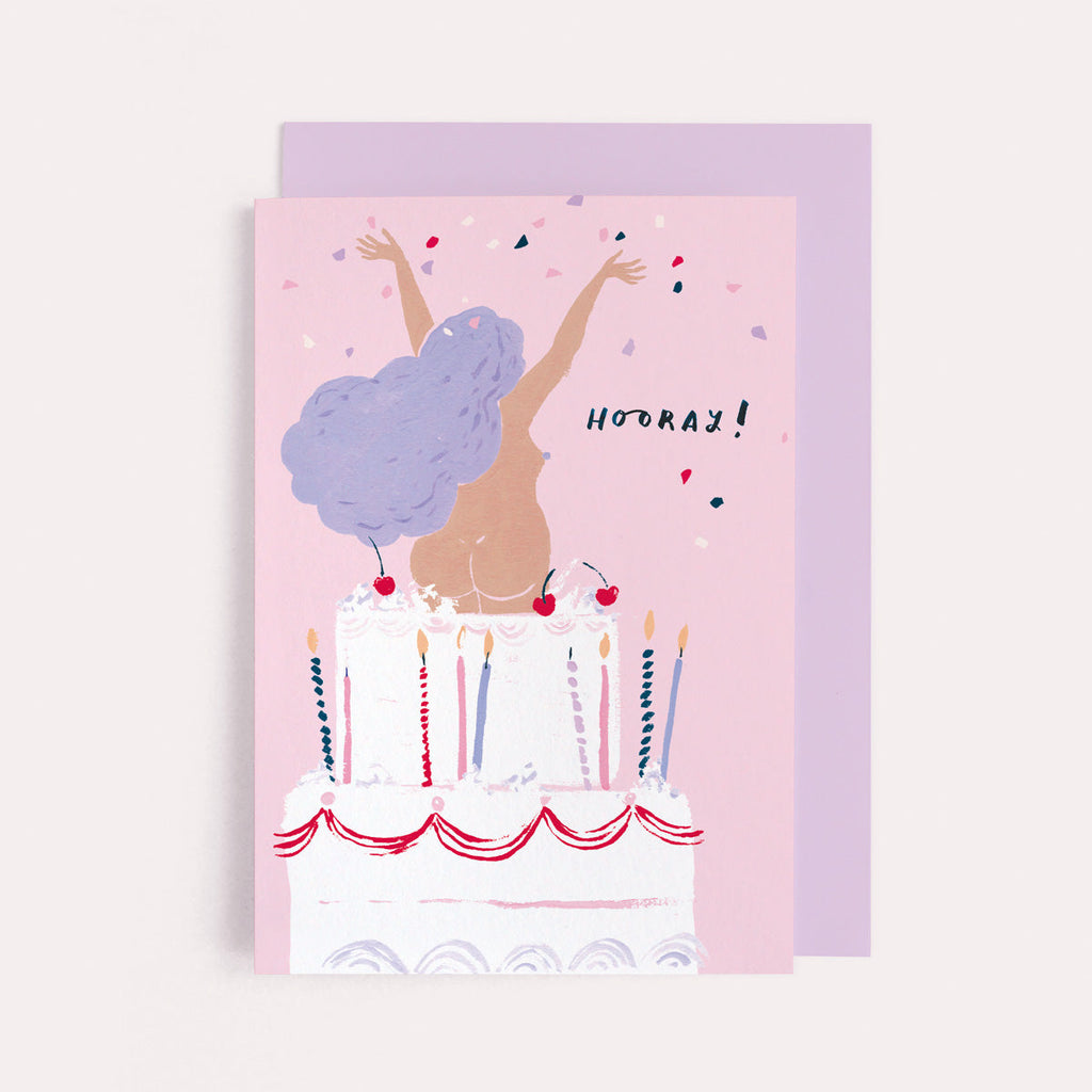 A girl jumping out of a giant cake on a rude funny womens birthday card from the female birthday card collection at Sister Paper Co.