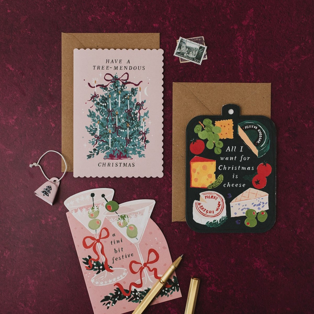 Have a Tree-mendous Christmas card with kraft envelope on a deep red background, with cheeseboard and martini Christmas cards