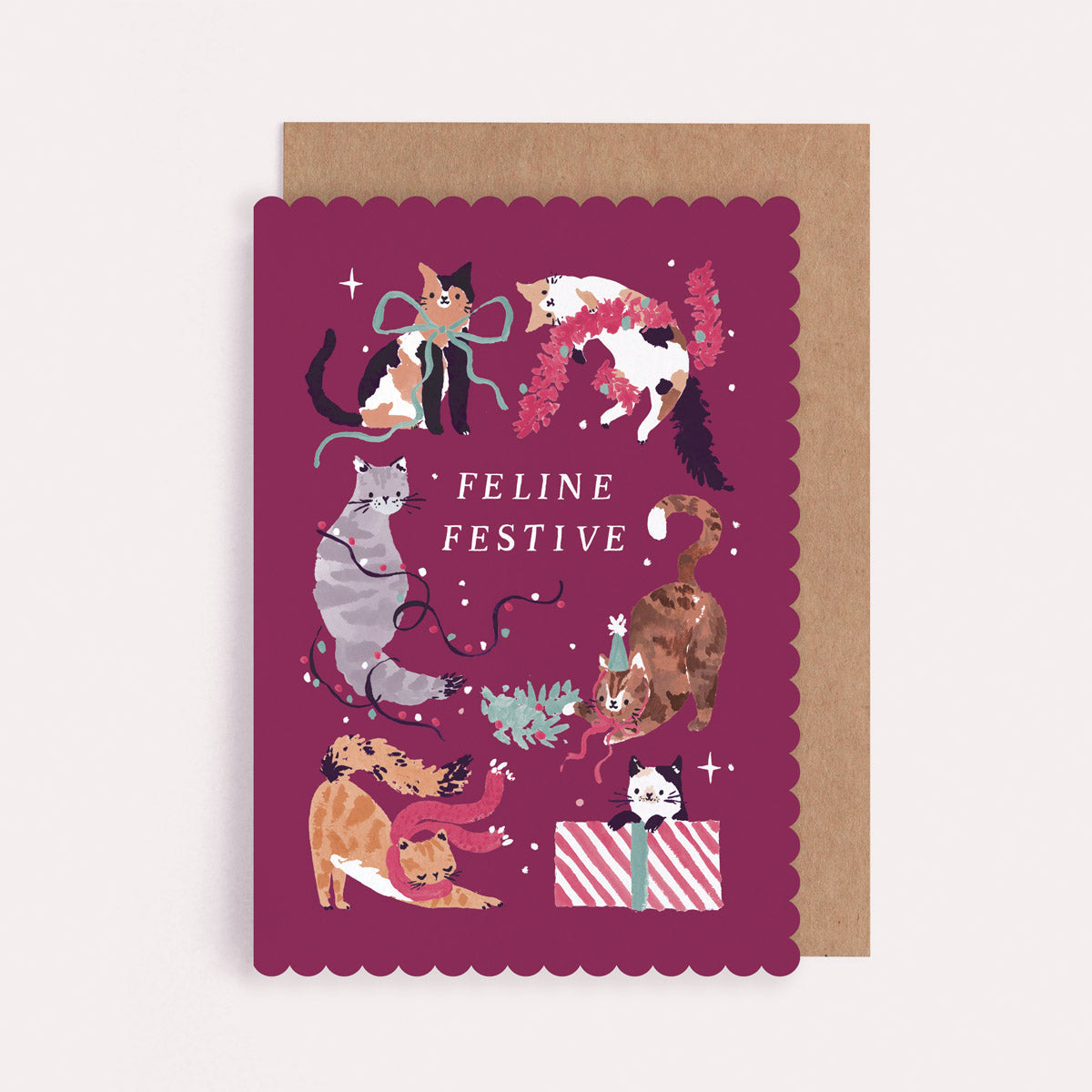 Christmas card with illustrations of cats and the text 'Feline Festive'  cut into a unique scallop shape.