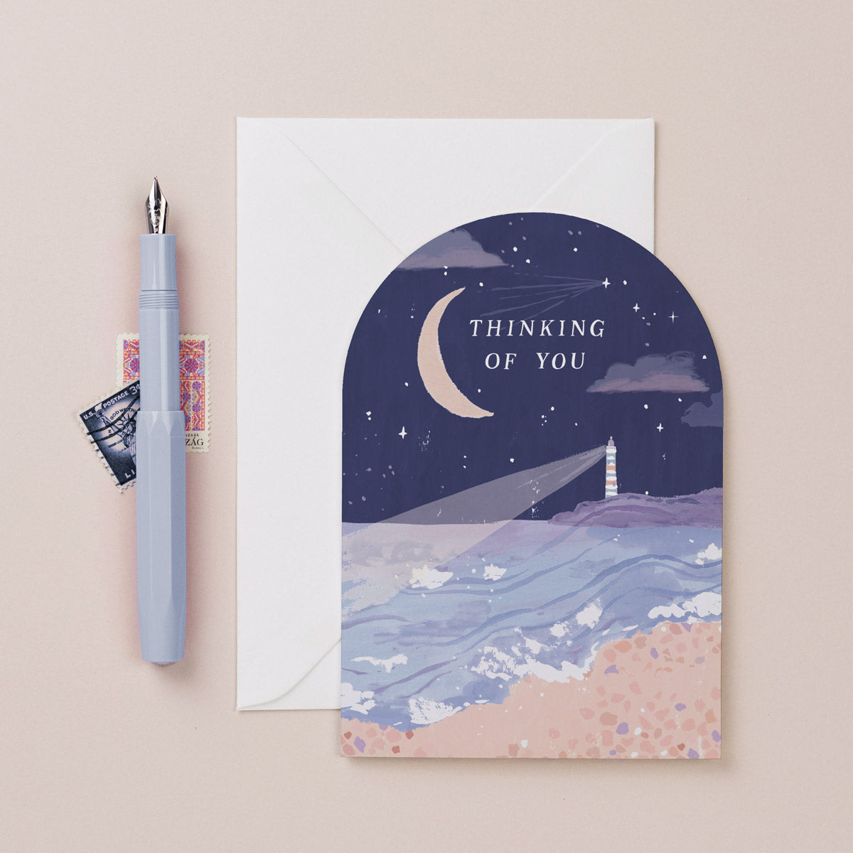 An illustrated thinking of you card featuring a lighthouse and a beach at night from the occasions card collection at Sister Paper Co.