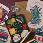 All I want for Christmas is cheese cheeseboard shaped card with a gold pen on a deep red background, with Bookish and mulled wine Christmas cards