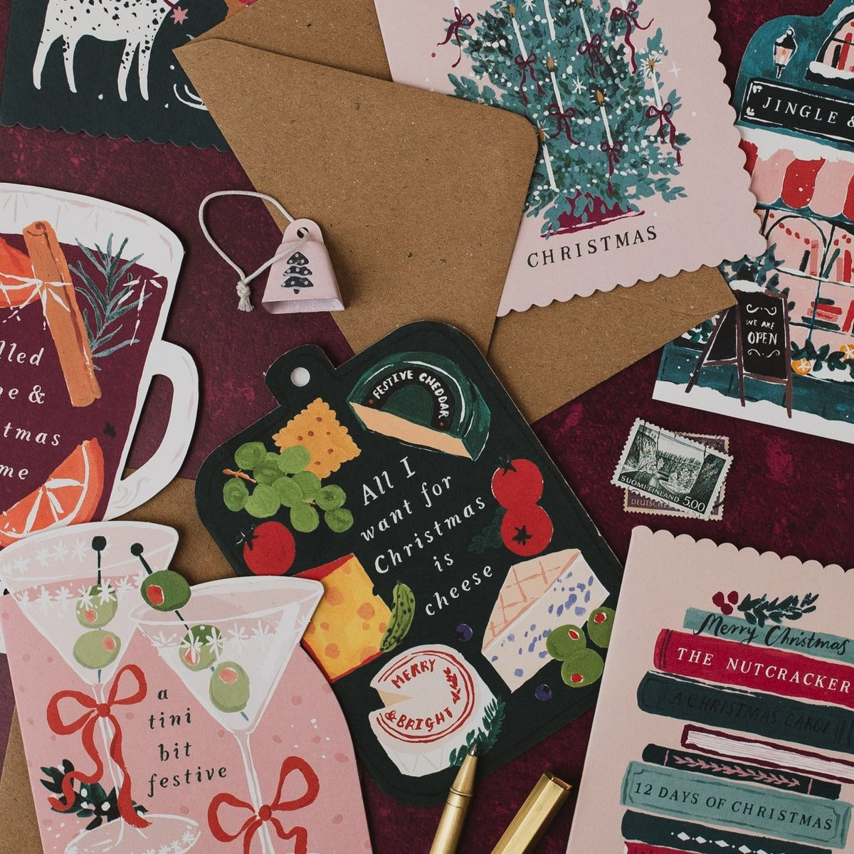 Mulled wine shaped Christmas card on a deep red background with martini, cheeseboard and Bookish Christmas cards