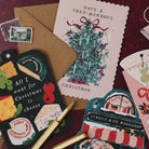 Jingle & Co bookshop shaped Christmas card on a deep red background with Tree-mendous and cheeseboard Christmas cards