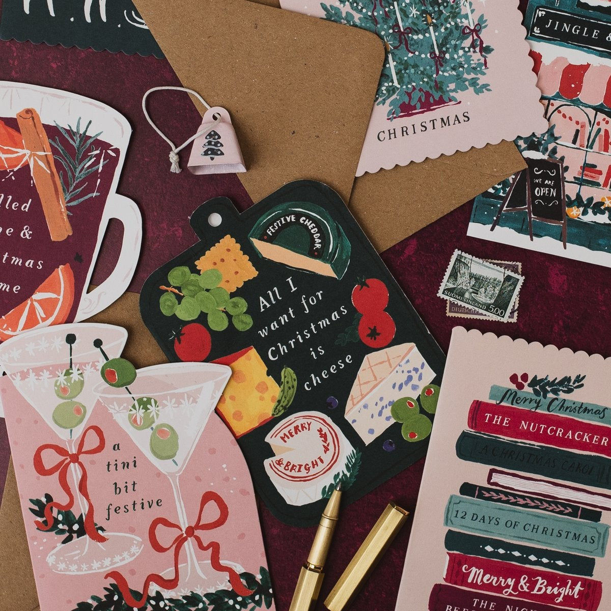 Cheeseboard shaped Christmas card with martini, mulled wine and Bookish Christmas cards on a deep red background
