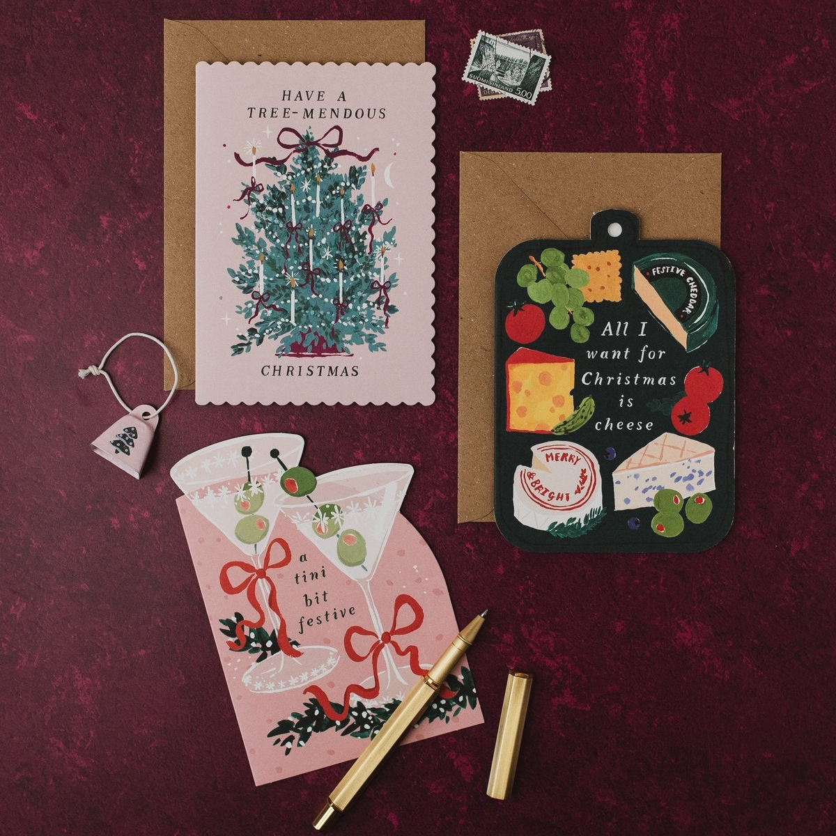 Tini Bit Festive martini Christmas card with Tree-mendous and cheeseboard Christmas cards and kraft envelopes on a deep red background