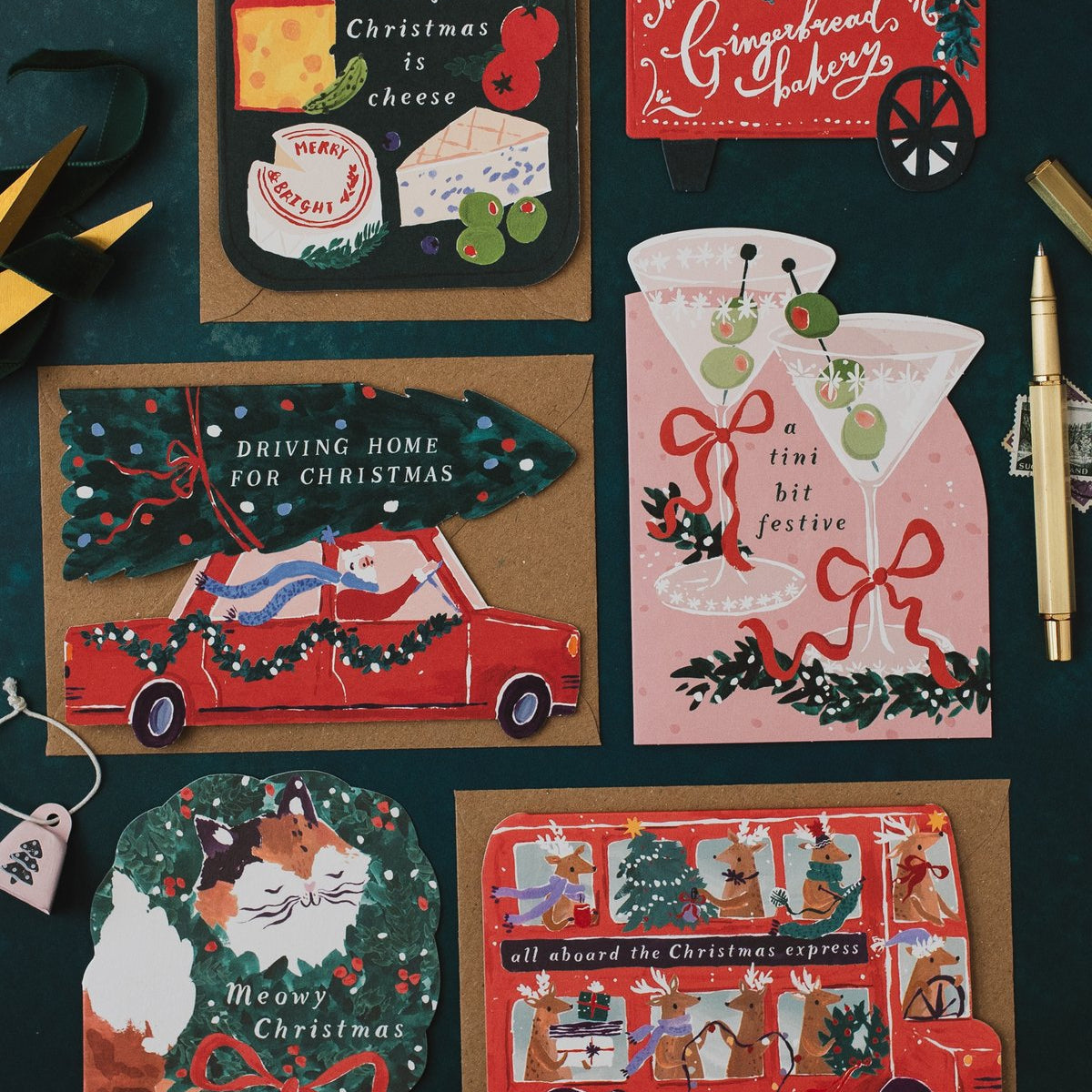 Driving Home for Christmas car shaped card on a dark teal background with martini, cheeseboard and gingerbread cart Christmas cards
