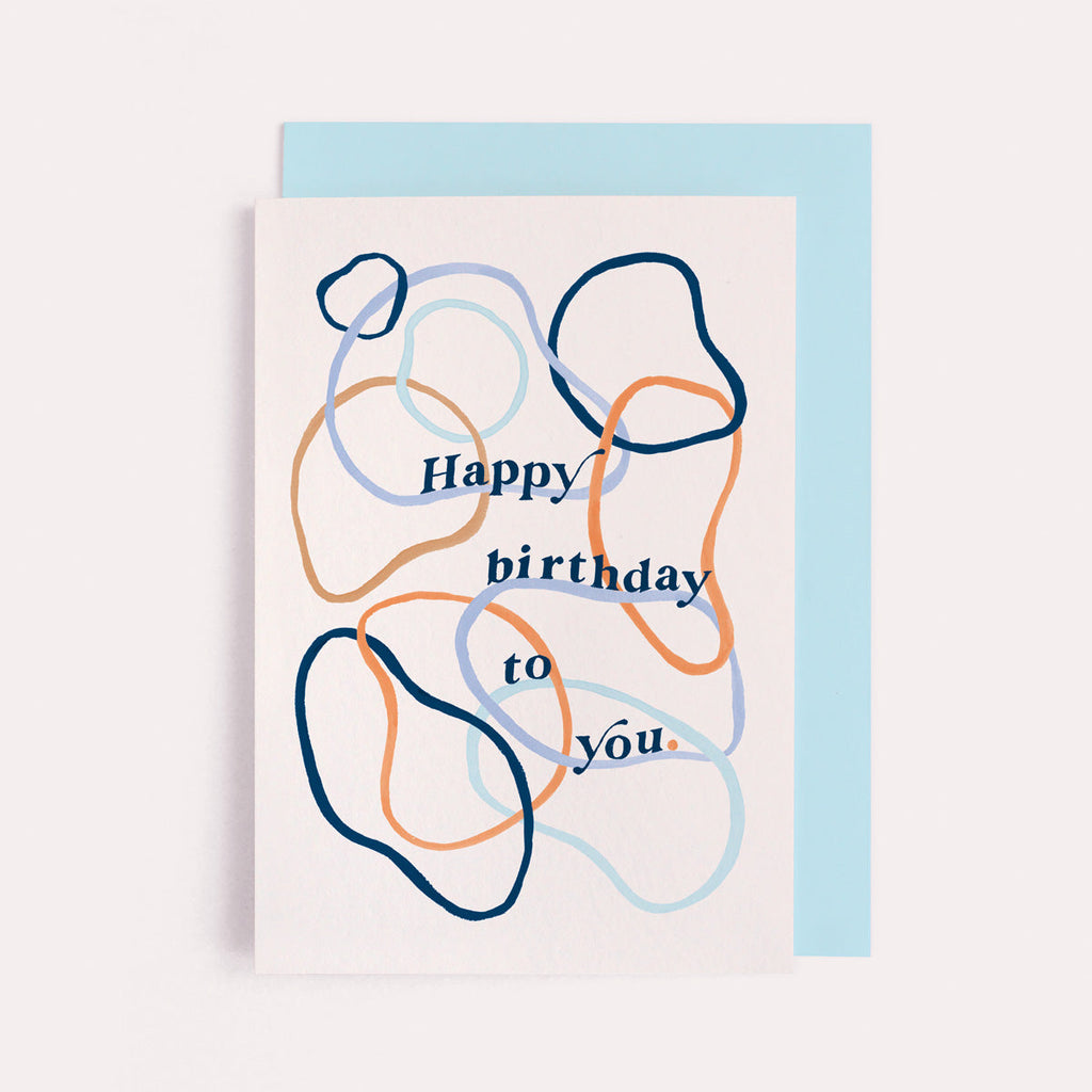 A simple birthday card with happy birthday lettering and abstract hoop pattern on a birthday card from the birthday card collection at Sister Paper Co.