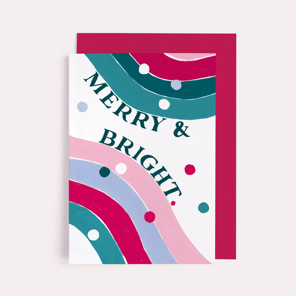 A rainbow with fun merry and bright lettering on a Christmas card from the colourful, rainbow Christmas card collection at Sister Paper Co.